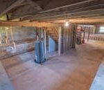 Empty basement with exposed beams and plumbing pipes, ideal for renovation.