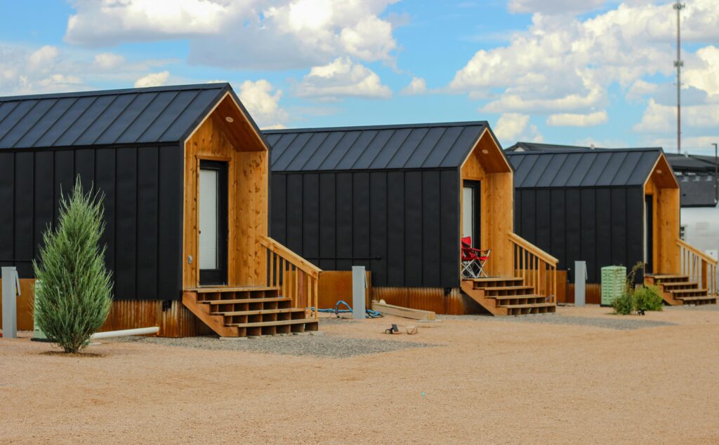 Row of modern black tiny houses in a desert setting under a cloudy sky.